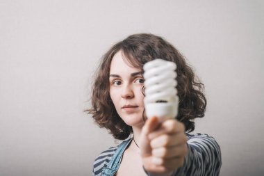 Kadın elinde yeni nesil bir ampul tutuyor.