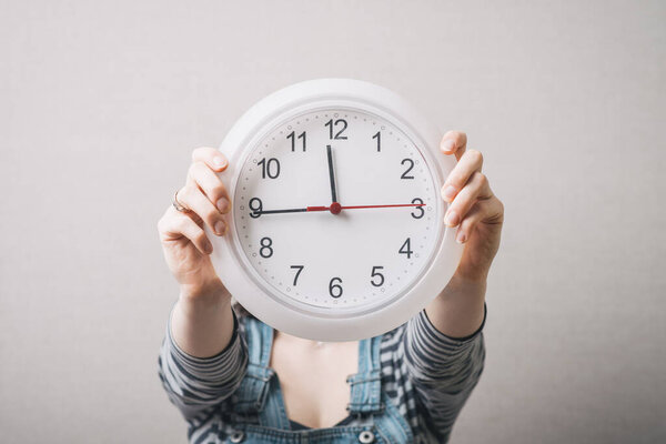 Woman holding a clock instead of a head. Gray background