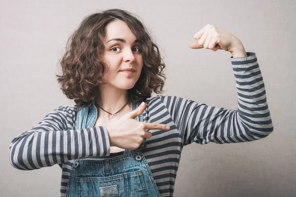 Frau Zeigt Spielerisch Die Muskeln Der Hand Auf Grauem Hintergrund — Stockfoto