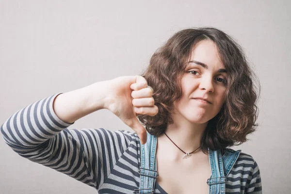 Vrouw Met Duim Naar Beneden Een Grijze Achtergrond — Stockfoto