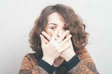 Gülüyor, elleri kapalı.