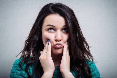 Kız parmaklarını yanaklarına bastırıyor.