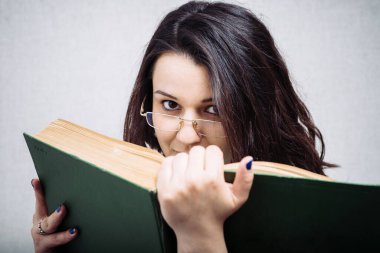 Gözlüklü kız kitap okuyor.