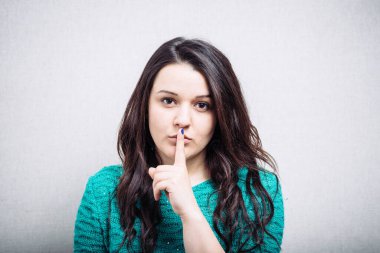 Kız parmağını dudaklarına koydu.