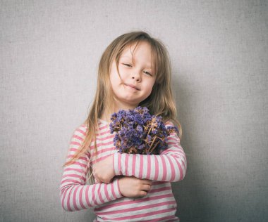 Stüdyoda elinde bir buket çiçekle küçük bir kız