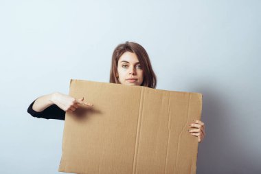 Kız bir karton kağıdın arkasından dışarı bakar.