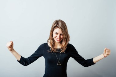 Gri arka planda kutlama yapan genç bir kadın.