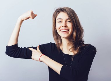 Kız, gri arka planda pazılarını gösteriyor.