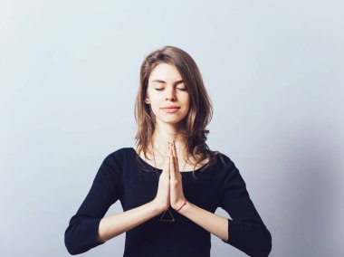 Gri bir arka planda dua eden kız