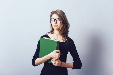 Büyük kitabı olan bir kadın. Gri bir arkaplanda.