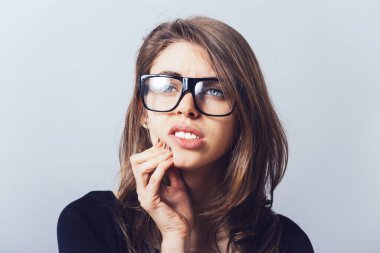 Gözlüklü bir kadın, dişleri acıyor.