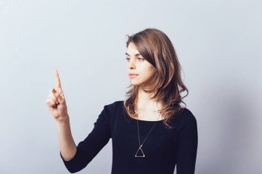 Kadın bu fikre parmak basıyor. Gri bir arkaplanda.