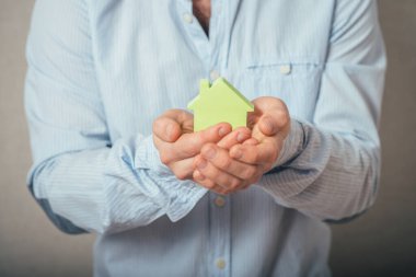 Kasklı genç adam kağıttan bir ev tutuyor.. 