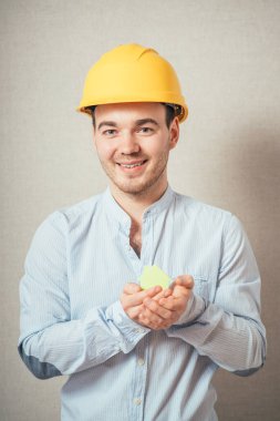 Kasklı genç adam kağıttan bir ev tutuyor.. 