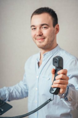 Elinde telefon tüpü olan ve gülümseyen bir adam.