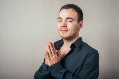 Bir erkek dua eder. Gri bir arkaplanda.