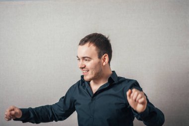 Adam sevinçten dans ediyor. Gri bir arkaplanda.