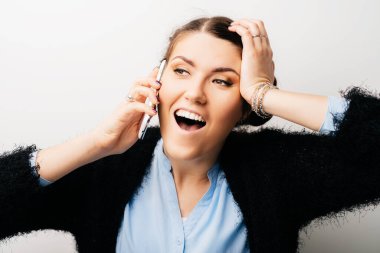 Kadın telefonda konuşuyor, eli kafasında, şaşırmış bir şekilde. Beyaz bir arkaplanda izole edilmiş