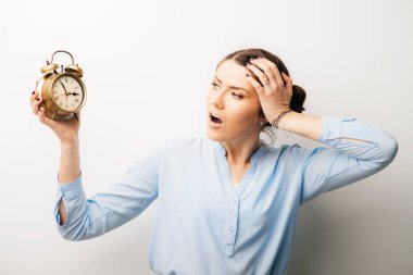 Saati ve eli başında olan bir kadın tatmin olmamış, geç kalmış. Beyaz bir arkaplanda izole edilmiş