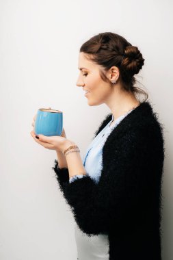 Büyük mavi fincanlı kadın, çay ya da kahve iç. Profil. Beyaz bir arkaplanda izole edilmiş
