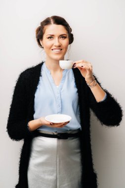 Küçük beyaz fincanlı bir kadın, çay ya da kahve içer. Beyaz bir arkaplanda izole edilmiş