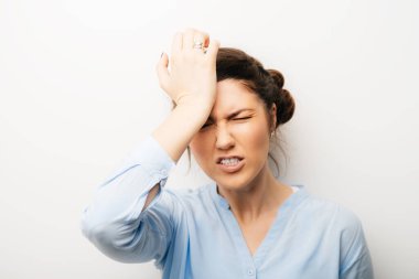 Başı ağrıyan kız, elleri başının üstünde. Beyaz bir arkaplanda izole edilmiş