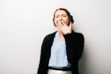 Kadın esniyor, uykulu, yorgun. Beyaz bir arkaplanda izole edilmiş