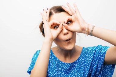 Kız ellerini dürbünle gösteriyor.