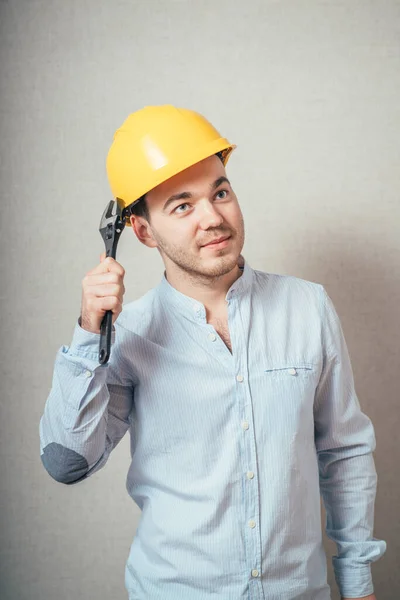 Man Met Gele Helm Een Moersleutel Een Grijze Achtergrond — Stockfoto