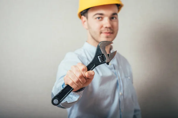 Man Met Gele Helm Een Moersleutel Een Grijze Achtergrond — Stockfoto