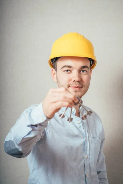 Man Met Gele Helm Met Sleutels Een Grijze Achtergrond — Stockfoto