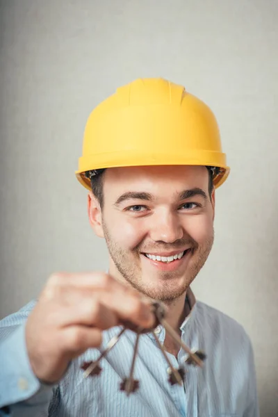 Man Met Gele Helm Met Sleutels Een Grijze Achtergrond — Stockfoto