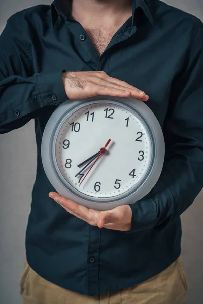 Ein Mann Hält Eine Wanduhr Auf Grauem Hintergrund — Stockfoto