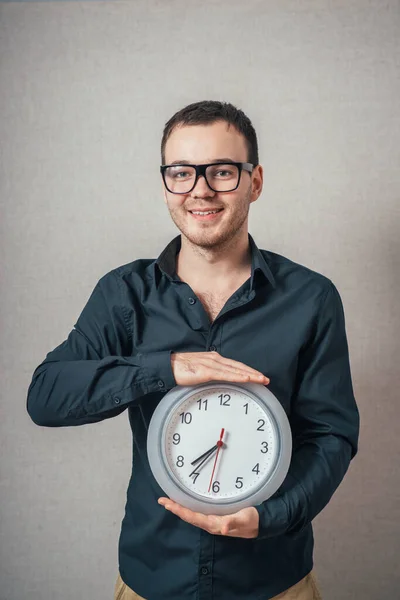 Ένας Άντρας Που Κρατάει Ένα Ρολόι Τοίχου Γκρι Φόντο — Φωτογραφία Αρχείου