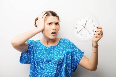 Kafasını tutan kocaman saati olan güzel bir kız.