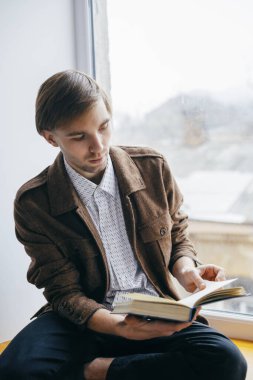 Genç adam kitap okuyor.