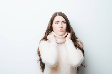 Beyaz arka planda, beyaz kazaklı, uzun saçlı güzel bir kız.