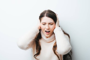 Güzel, uzun saçlı bir kızın başı ağrıyordu ve ellerini beyaz bir arka planda tutuyordu.