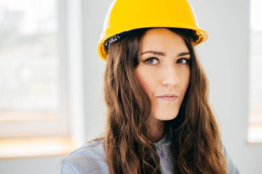 Sarı başlıklı kız büyük bir pencerenin yanında.