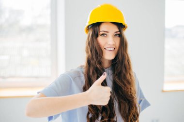 Sarı başlıklı genç mühendis pencereye doğru işaret veriyor.