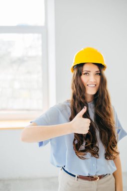 Sarı başlıklı genç mühendis pencereye doğru işaret veriyor.