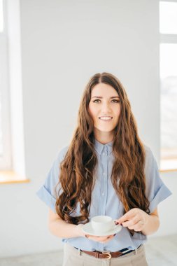 Elinde çay olan kadın pencerenin yanında dinleniyor.