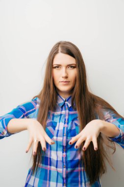 Elleri gergin ve şaşırmış genç, güzel bir kadın. Beyazda izole edilmiş.