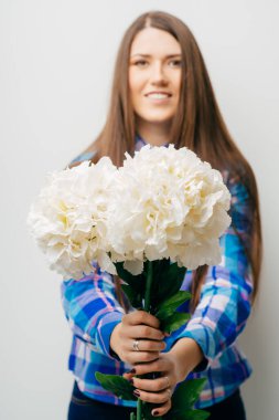 Beyaz arka planda saklanmış çiçekleri gösteren bir kadın. Güzel, taze, melez Asyalı beyaz kadın model, şirin yaz elbisesi içinde..