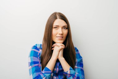 Neşeli gülümseyen neşeli genç bir kadının yakından çekilmiş portresi. Eli çenesinde, hayal dünyasında, beyaz arka planda soyutlanmış bir şekilde yukarı bakıyor. Olumlu insani duygular, yüz ifadeleri