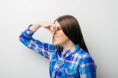 Güzel genç bayan burnu eliyle kapatıyor. Bu da gösteriyor ki, beyaz bir şeyin üstünde izole edilmiş pis bir koku var.