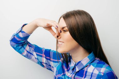 Güzel genç bayan burnu eliyle kapatıyor. Bu da gösteriyor ki, beyaz bir şeyin üstünde izole edilmiş pis bir koku var.