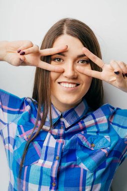 Kız gözlerinin etrafında iki parmak gösteriyor.