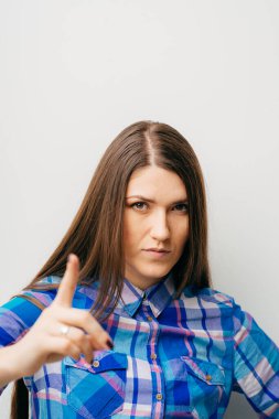 Beyaz arka planda genç kız işaret parmağını gösteriyor.