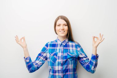 Beyaz bir arka planda genç bir kız meditasyon yapıyor.